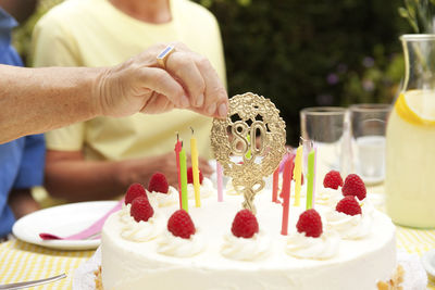 Hand removimg 80th birthday decoration from cake