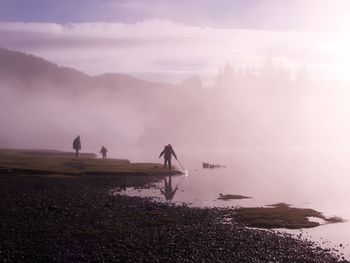 People on lake against sky