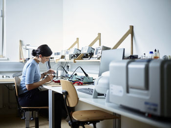 Engineer sitting on chair working in electronics laboratory