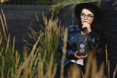 Portrait of young woman standing against plants