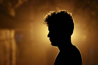 Close-up portrait of silhouette man standing against orange sunset