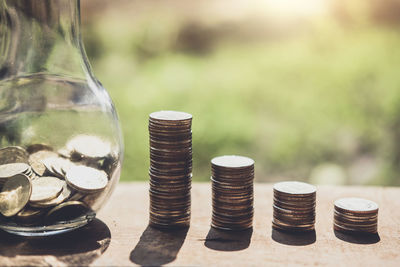 Close-up of coins stacks by jar on table