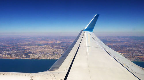 Aerial view of airplane wing against clear blue sky