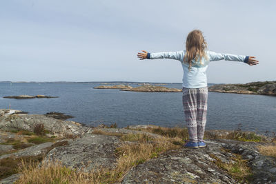 Rear view of woman standing by sea against sky