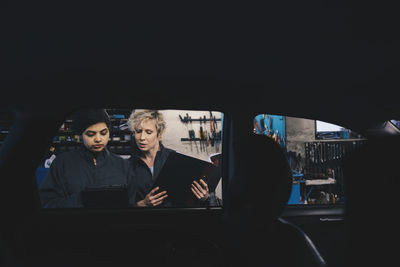 Reflection of woman using mobile phone while sitting in bus