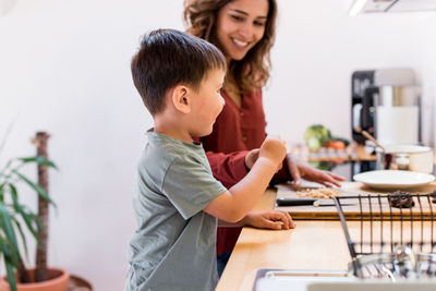 Mother preparing food by son in kitchen