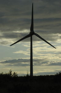 Wind turbines on field against cloudy sky