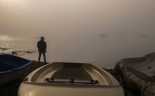 Silhouette of adult man with fishing boats on beach during sunrise. almeria, spain