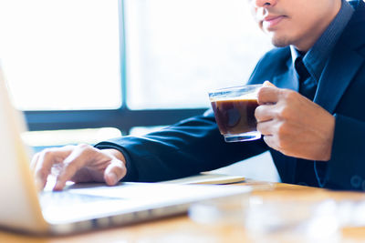 Midsection of man using mobile phone on table