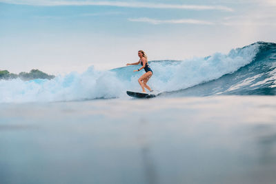 Full length of man surfing on sea against sky