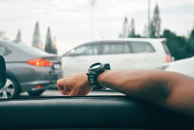 Cropped hand of person wearing wristwatch on car window