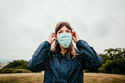 Portrait of young woman standing against sky