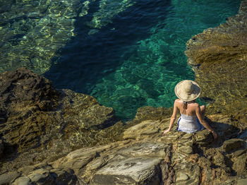 High angle view of woman on rock by sea