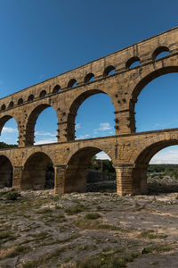 Low angle view of historical building against blue sky aqueduct pont du gard