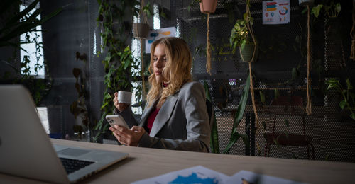 Portrait of young woman using digital tablet while sitting at office