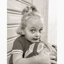 Portrait of cute girl holding soccer ball while at home