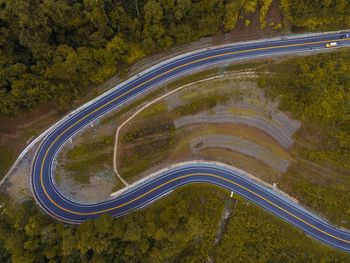 Aerial view of winding road amidst trees in forest