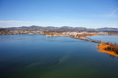 Aerial view of city by sea against blue sky