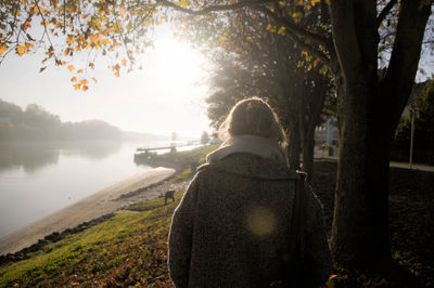 Rear view of woman on field by lake during winter