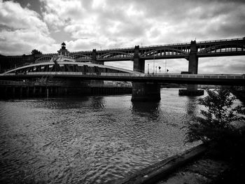 Bridge over river in city against sky