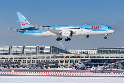 Airplane flying in city against sky