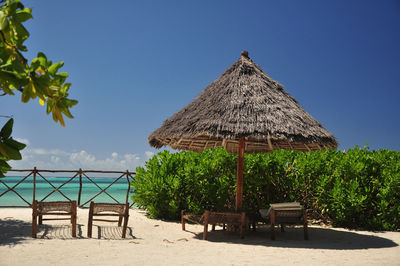 Chairs on beach against clear blue sky