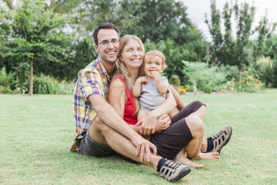 Portrait of smiling family sitting on field