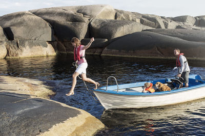 Man looking at woman jumping from motorboat on rock formation