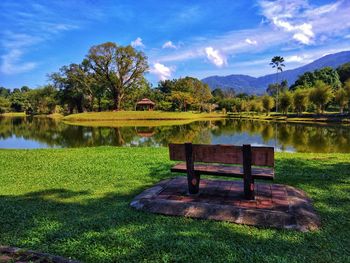 Bench by lake against sky