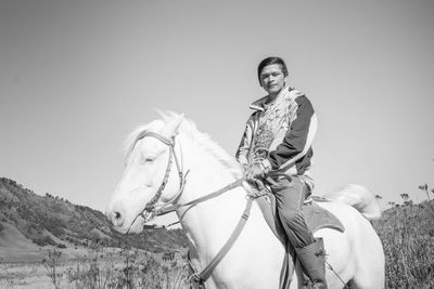 Low angle portrait of man riding horse against sky