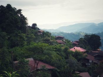 Houses by trees and mountains against sky
