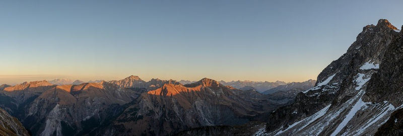 Scenic view of snowcapped mountains against clear sky during sunset