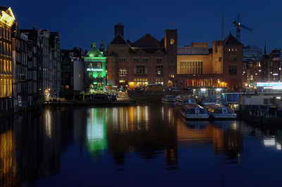 Sailboats moored on illuminated buildings in city at night