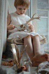 Full length of cute baby girl sitting on windowsill