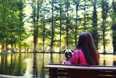 Woman with dog sitting by lake