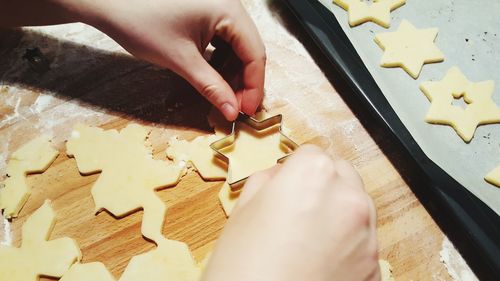 Cropped hands preparing cookies on cutting board