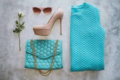 Set of clothes on the white background. turquoise bag, sweater, beige high hills shoes, sunglasses