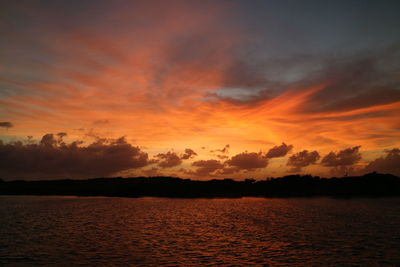 Scenic view of sea against dramatic sky during sunset