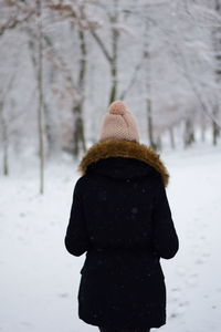 Rear view of woman wearing warm clothing while standing on field during winter