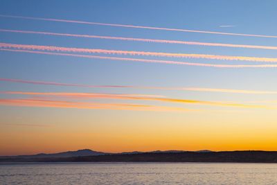 Low angle view of vapor trails in sky during sunset