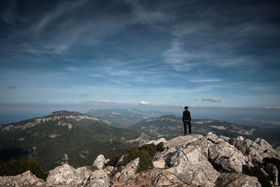 Rear view of man standing on mountain against sky