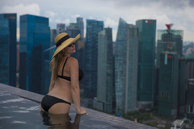 Woman swimming in infinity pool against buildings