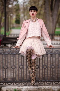 Portrait of woman standing against railing