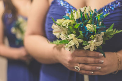 Midsection of two bridesmaids holding flowers
