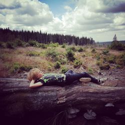 Rear view of woman lying down on land against sky