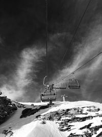 Ski lift over snowcapped mountains against sky