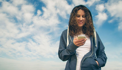 Portrait of young woman holding coffee cup against sky