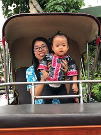 Portrait of mother carrying baby girl while sitting in vehicle