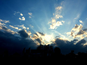 Low angle view of silhouette people against blue sky