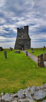 Old ruin building on field against cloudy sky